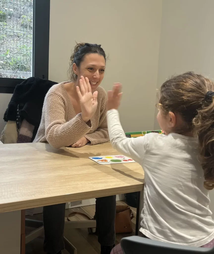 Photographie de Vanessa Riesgo en évaluation comportementale qui tape dans la main d'une enfant pour valoriser sa participation