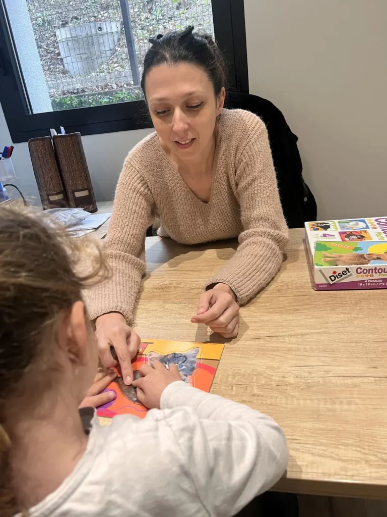 Photographie de Vanessa Riesgo guidant une enfant à réaliser un puzzle